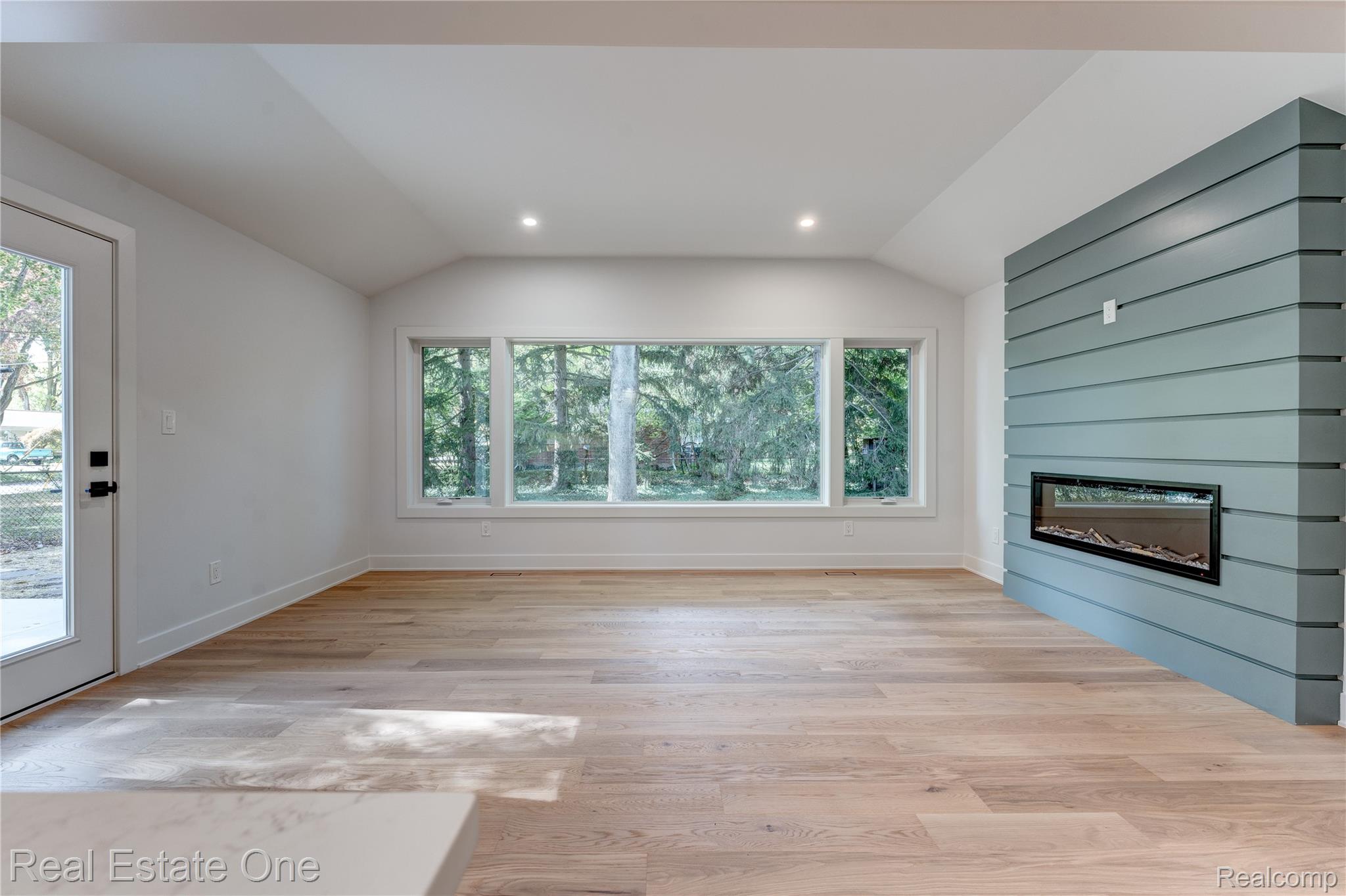 786 South Cranbrook Road Bloomfield Hills, MI 48301 - Photo 9 of 38 Unfurnished living room with a glass covered fireplace, light wood-type flooring, vaulted ceiling, healthy amount of natural light, and recessed lighting