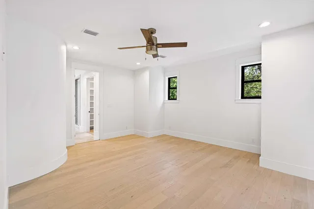 an empty room with a ceiling fan and window