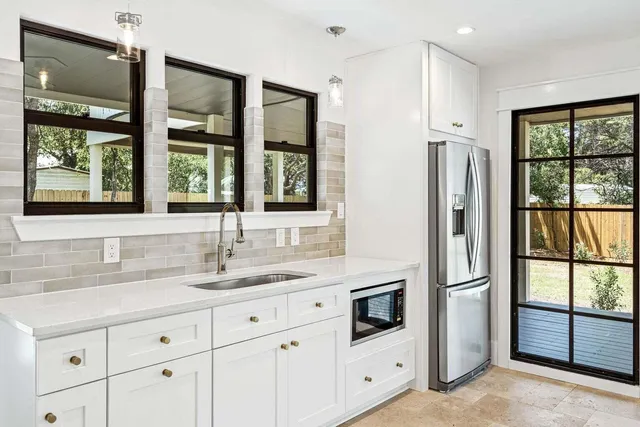 a kitchen with white cabinets and window