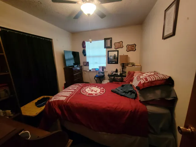a bedroom with bed and a flat tv screen on dresser
