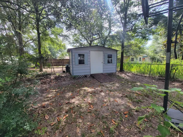 a view of backyard with large trees and wooden fence