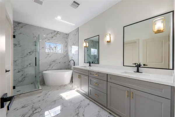a spacious bathroom with a bathtub shower sink mirror and toilet