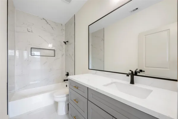 a bathroom with a sink a toilet a mirror and shower