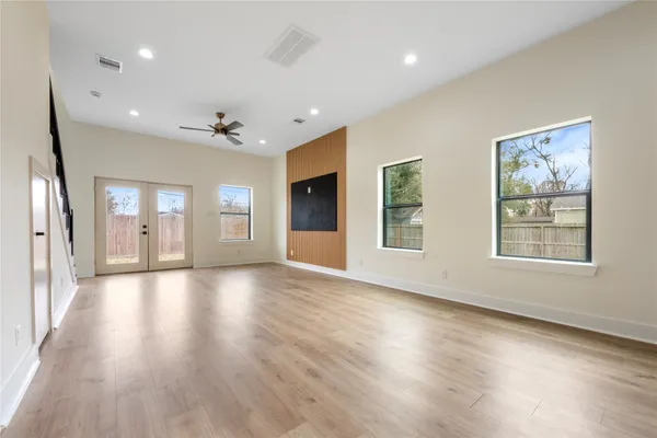 an empty room with wooden floor and windows