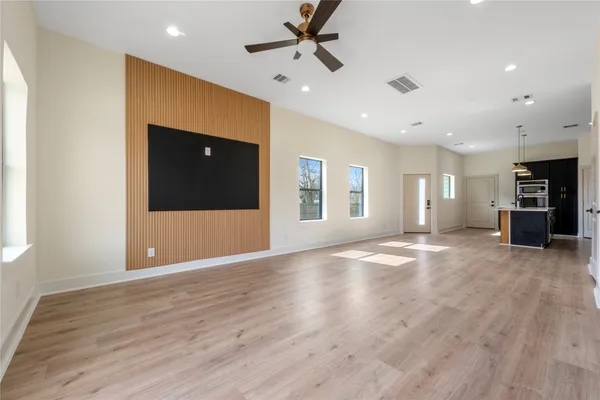 a view of an empty room with window and a kitchen