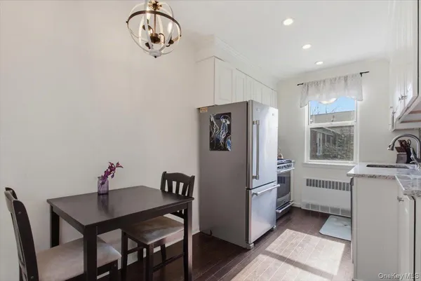 a kitchen with stainless steel appliances granite countertop a refrigerator a sink dishwasher a dining table and chairs with wooden floor