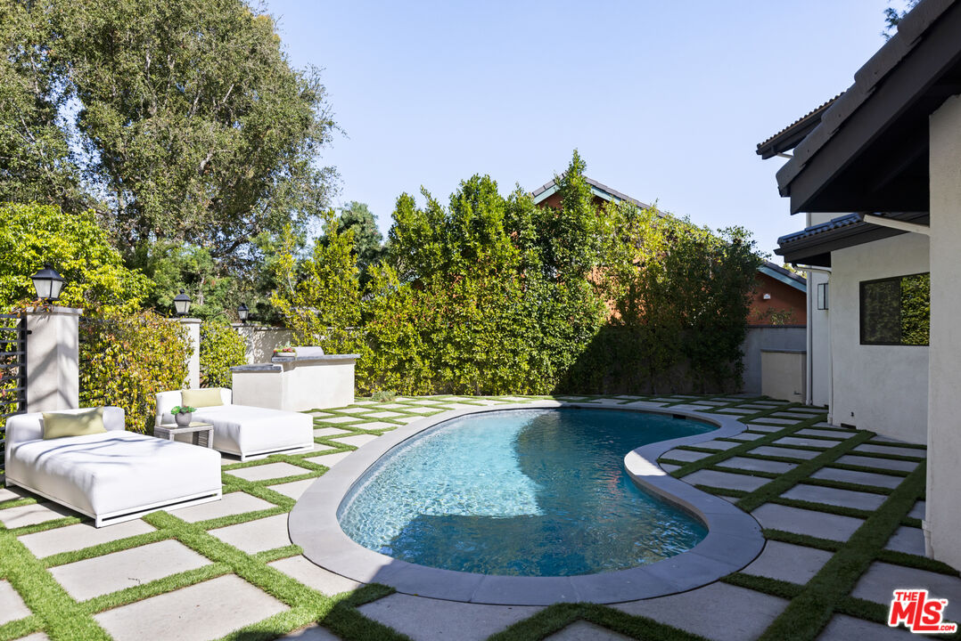 16167 Meadowcrest Road Sherman Oaks, CA 91403 - Photo 26 of 31 a view of a backyard with table and chairs potted plants and a palm tree