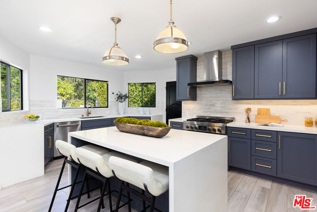 16167 Meadowcrest Road Sherman Oaks, CA 91403 - Photo 5 of 31 a kitchen with stainless steel appliances a stove a sink a dining table and chairs