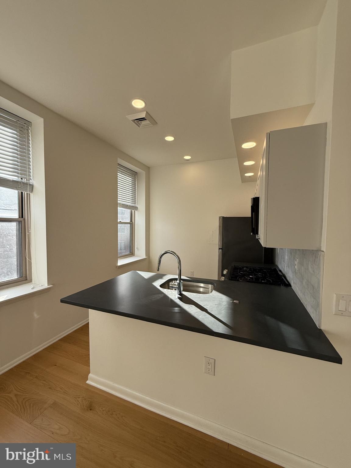 261-269 South 9th Street, Unit 504 Philadelphia, PA 19107 - Photo 18 of 27 a kitchen with a sink and a stove with wooden floor