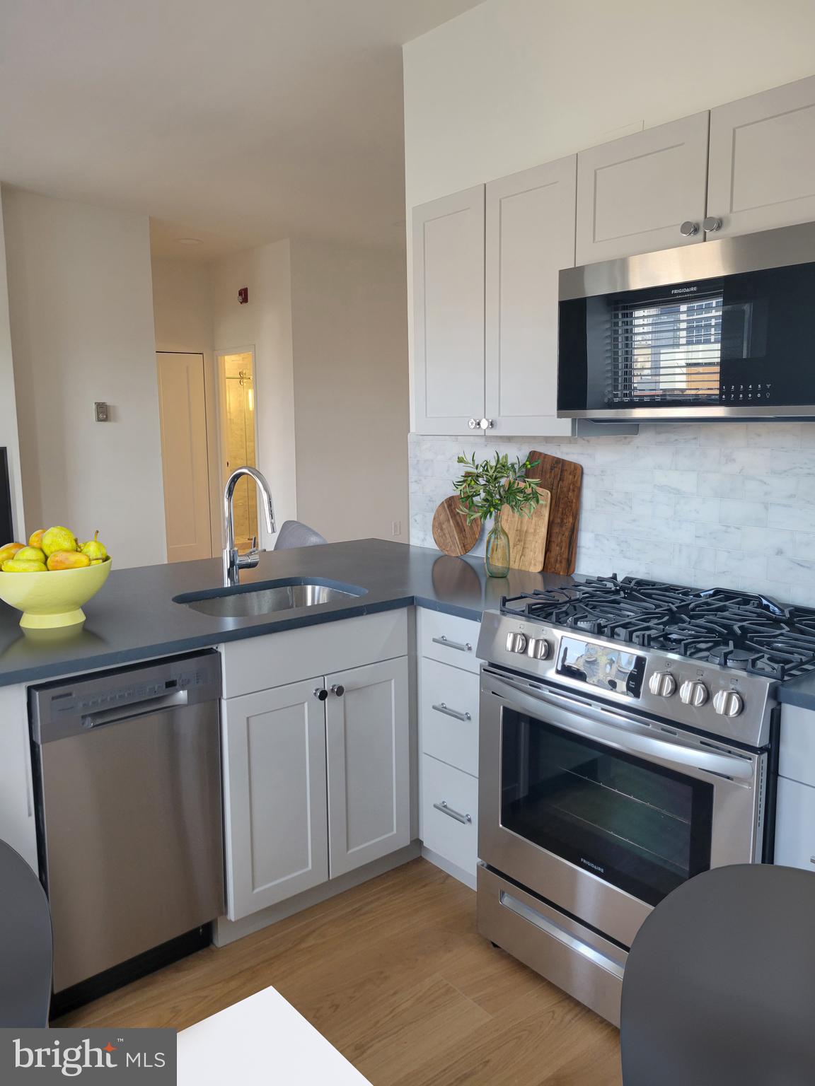 261-269 South 9th Street, Unit 504 Philadelphia, PA 19107 - Photo 5 of 27 a kitchen with stainless steel appliances a stove a sink and a microwave