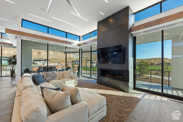 3558 South Cypress Road Hurricane, UT 84737 - Photo 5 of 57 Living room featuring expansive windows, a healthy amount of sunlight, light wood-type flooring, and a fireplace