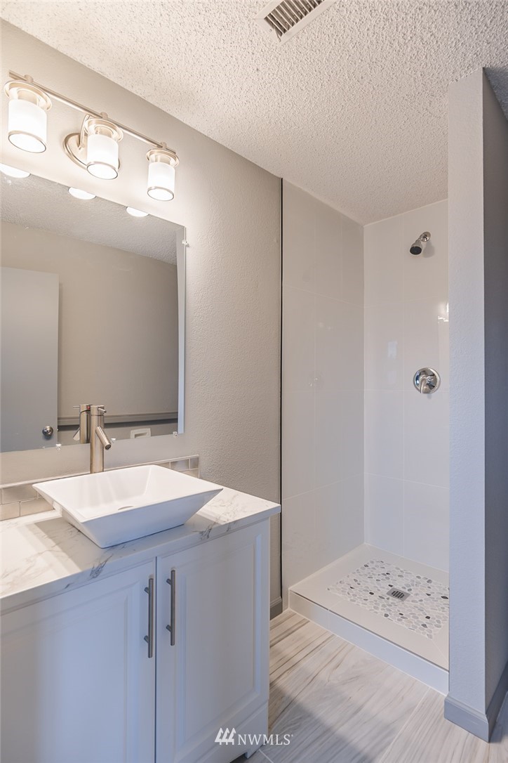 8037 Valley Road Northeast Moses Lake, WA 98837 - Photo 34 of 39 a bathroom with a granite countertop sink a mirror and a shower