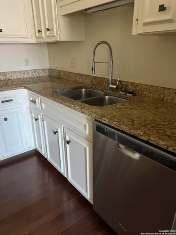 a close view of a sink and dishwasher with wooden floor