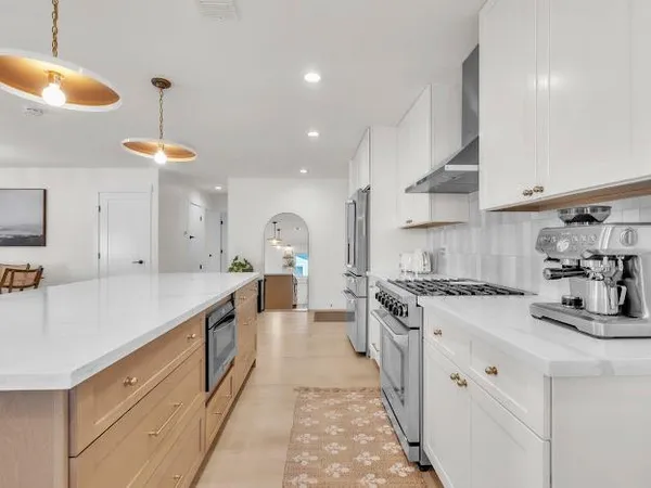 a large kitchen with stainless steel appliances granite countertop a sink a stove and a refrigerator