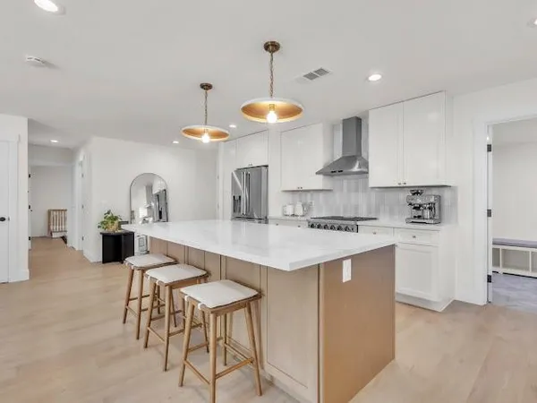 a kitchen with stainless steel appliances a table and chairs in it