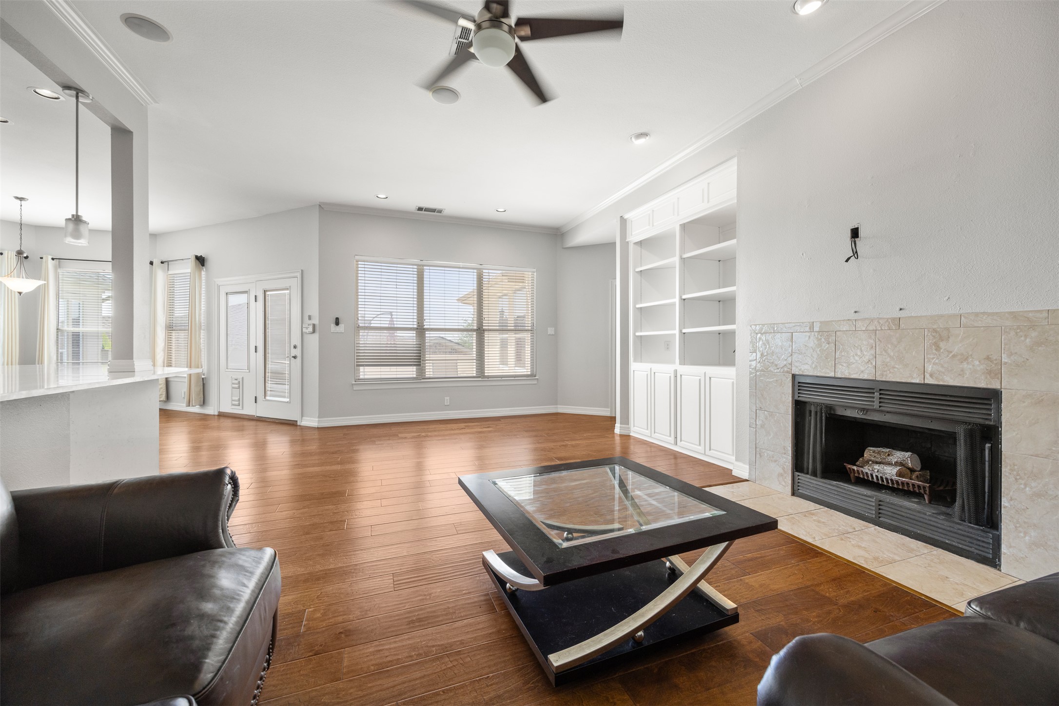 9300 Simmons Road Austin, TX 78759 - Photo 4 of 17 A welcoming living area boasts warm wood flooring, a ceiling fan, and a tiled fireplace for cozy gatherings.