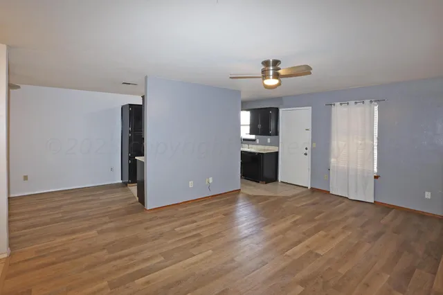 a view of an empty room with wooden floor and a window