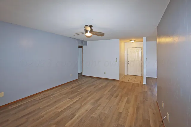 a view of empty room with wooden floor and fan