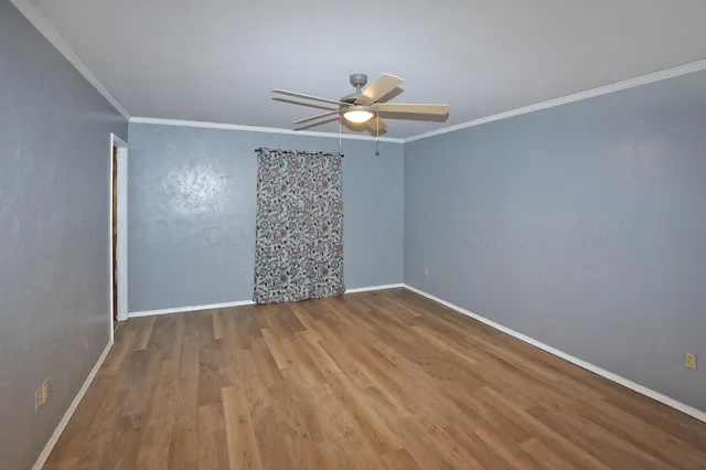 a view of an empty room with window and wooden floor