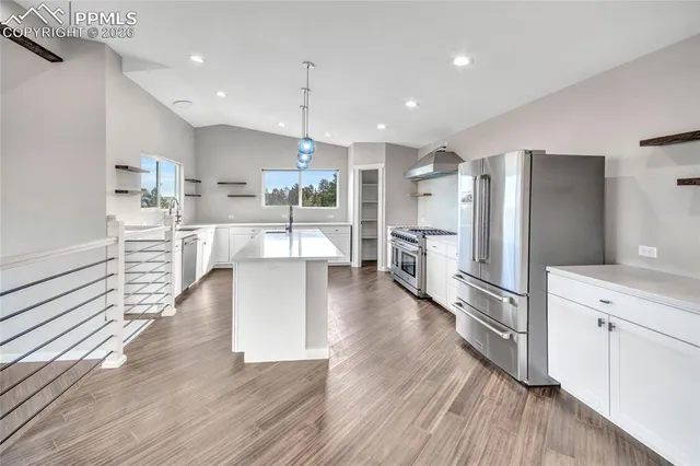 a kitchen with stainless steel appliances a stove a sink a chimney and a wooden floor