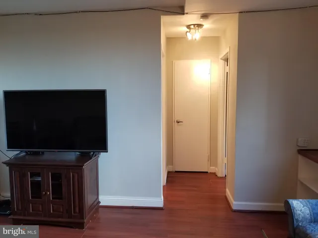 a view of a hallway with wooden floor and a flat screen tv