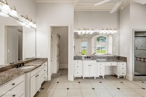 a spacious en suite bathroom with a granite countertop double sink and a mirror