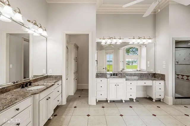 a spacious en suite bathroom with a granite countertop double sink and a mirror