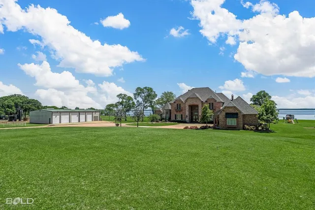 a front view of a house with garden and trees
