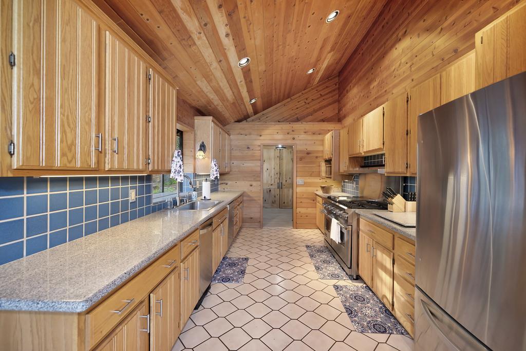 6301 Canyon Creek Road Georgetown, CA 95635 - Photo 18 of 87 kitchen with stainless steel appliances, vaulted ceiling, light stone counters, instant hot water, 6 burner viking stove, wood ceiling, and wood walls