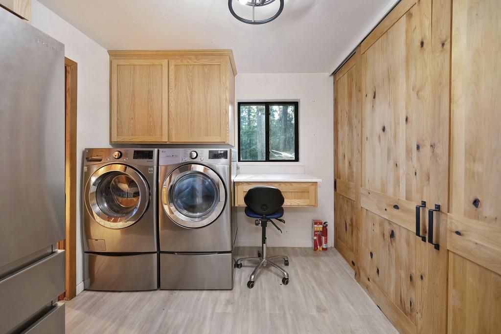 6301 Canyon Creek Road Georgetown, CA 95635 - Photo 33 of 87 laundry room featuring light wood-style floors, washer and clothes dryer, and cabinet space