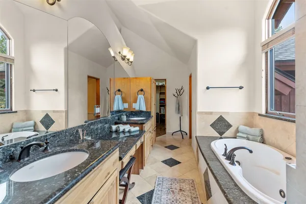 a bathroom with a granite countertop tub a double vanity sink and a large mirror