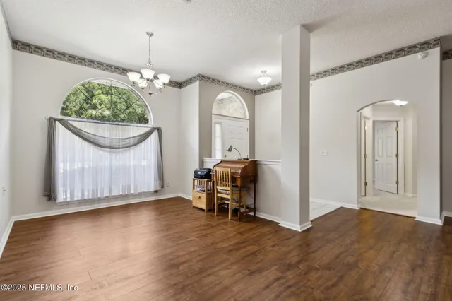 a view of a livingroom with a chandelier wooden floor and a chandelier