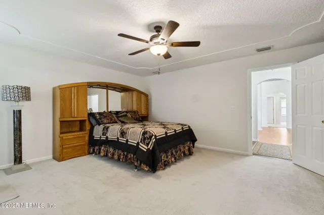 a spacious bedroom with a bed and a chandelier
