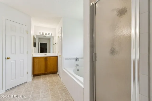 a spacious bathroom with a double vanity sink a mirror and a bathtub