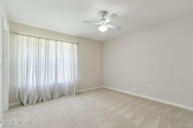 an empty room with a ceiling fan and a window