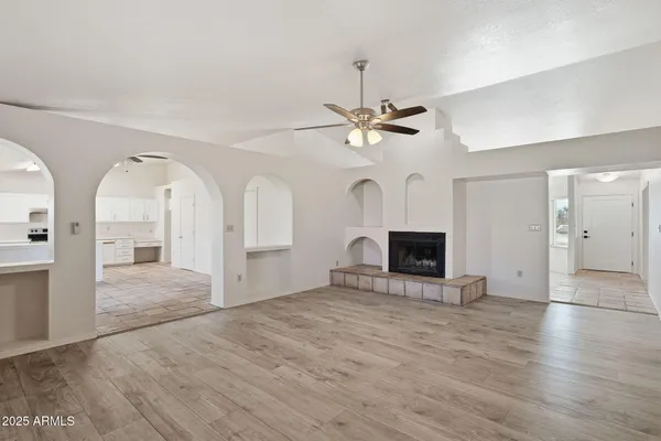a view of an empty room with a fireplace and chandelier fan