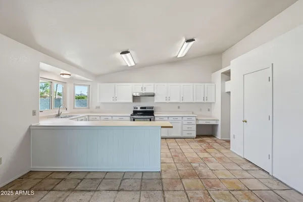 a kitchen with stainless steel appliances a sink a stove a refrigerator cabinets and a window