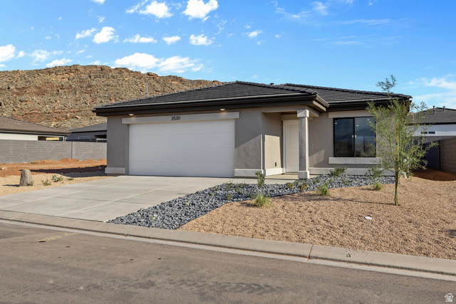 1597 South Fins Road, Unit 4177 Washington, UT 84780 - Photo 4 of 33 Contemporary stucco exterior with an integrated garage, dark tile roofing, and a prominent mountain backdrop