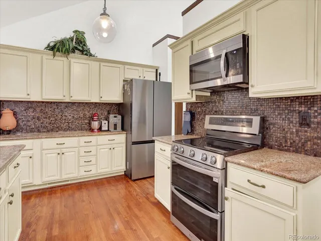 a kitchen with granite countertop cabinets stainless steel appliances and wooden floor