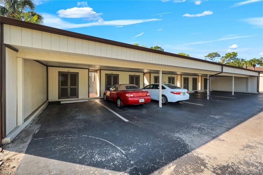 5857 Rattlesnake Hammock Road, Unit 101 Naples, FL 34113 - Photo 19 of 19 Covered parking structure featuring multiple bays, a light-colored facade, dark trim, and individual entryways