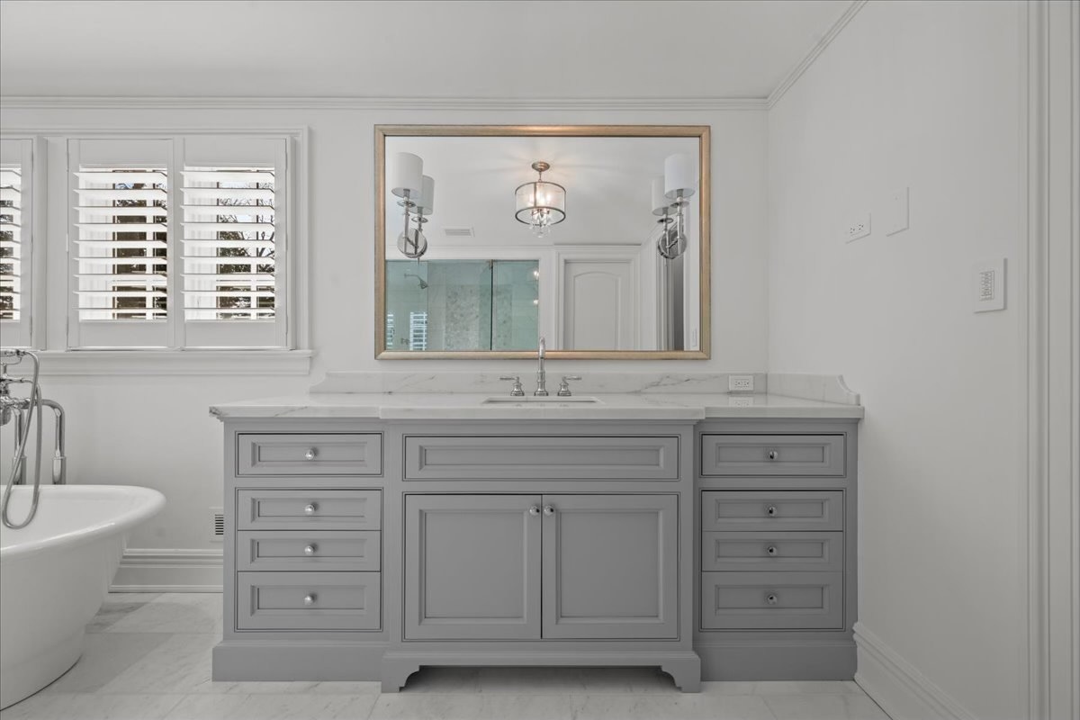 745 East Woodland Road Lake Forest, IL 60045 - Photo 44 of 77 a bathroom with a granite countertop sink a large mirror and a bathtub
