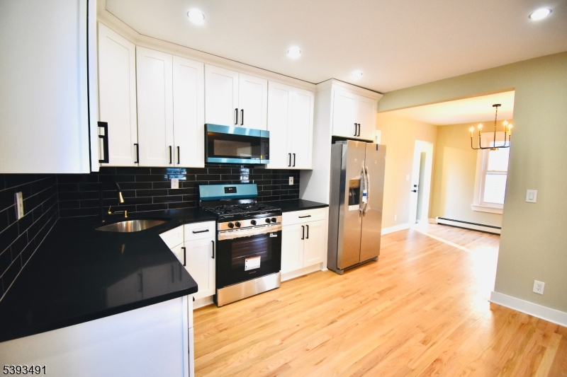 1222 West 3rd Street Plainfield, NJ 07063 - Photo 18 of 50 a kitchen with granite countertop a refrigerator and a stove top oven
