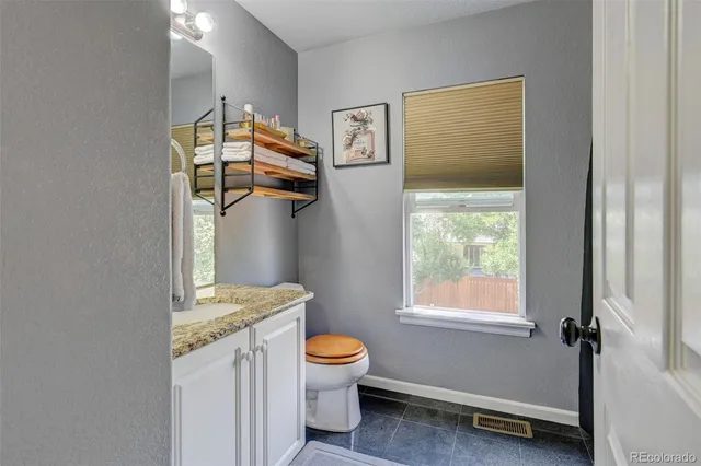 a bathroom with a granite countertop toilet a sink and a window