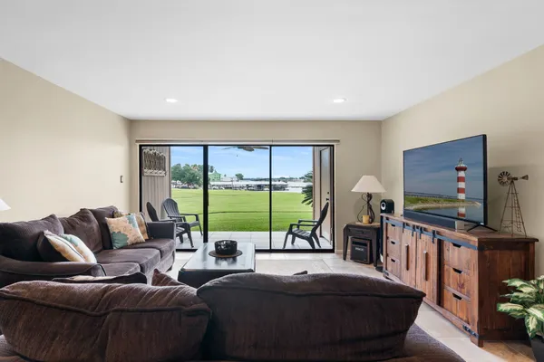 a living room with furniture a flat screen tv and a floor to ceiling window