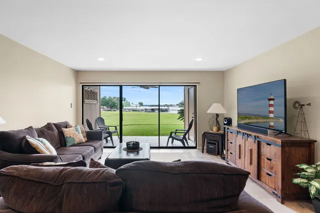 a living room with furniture a flat screen tv and a floor to ceiling window