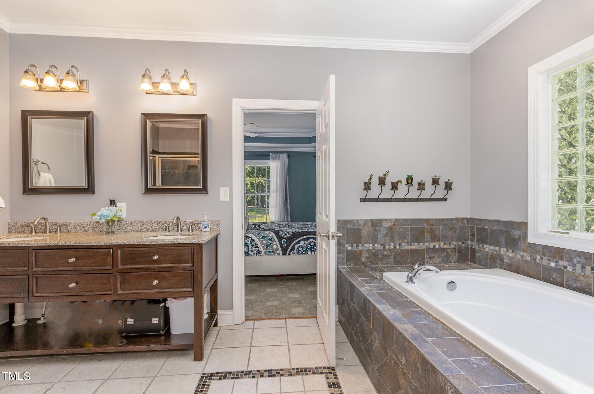 679 Roberts Chapel Road Stem, NC 27581 - Photo 11 of 28 a spacious bathroom with a tub a double vanity sink and a mirror