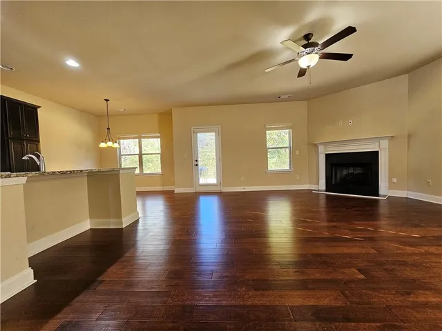 an empty room with wooden floor fireplace and windows
