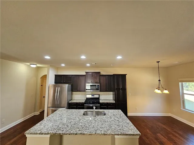 a view of kitchen with stainless steel appliances granite countertop a stove top oven a refrigerator a sink and dishwasher with wooden floor