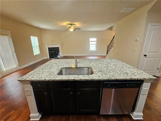 a kitchen with kitchen island granite countertop a sink and a refrigerator