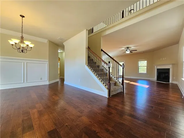 a view of a room with wooden floor chandelier and windows